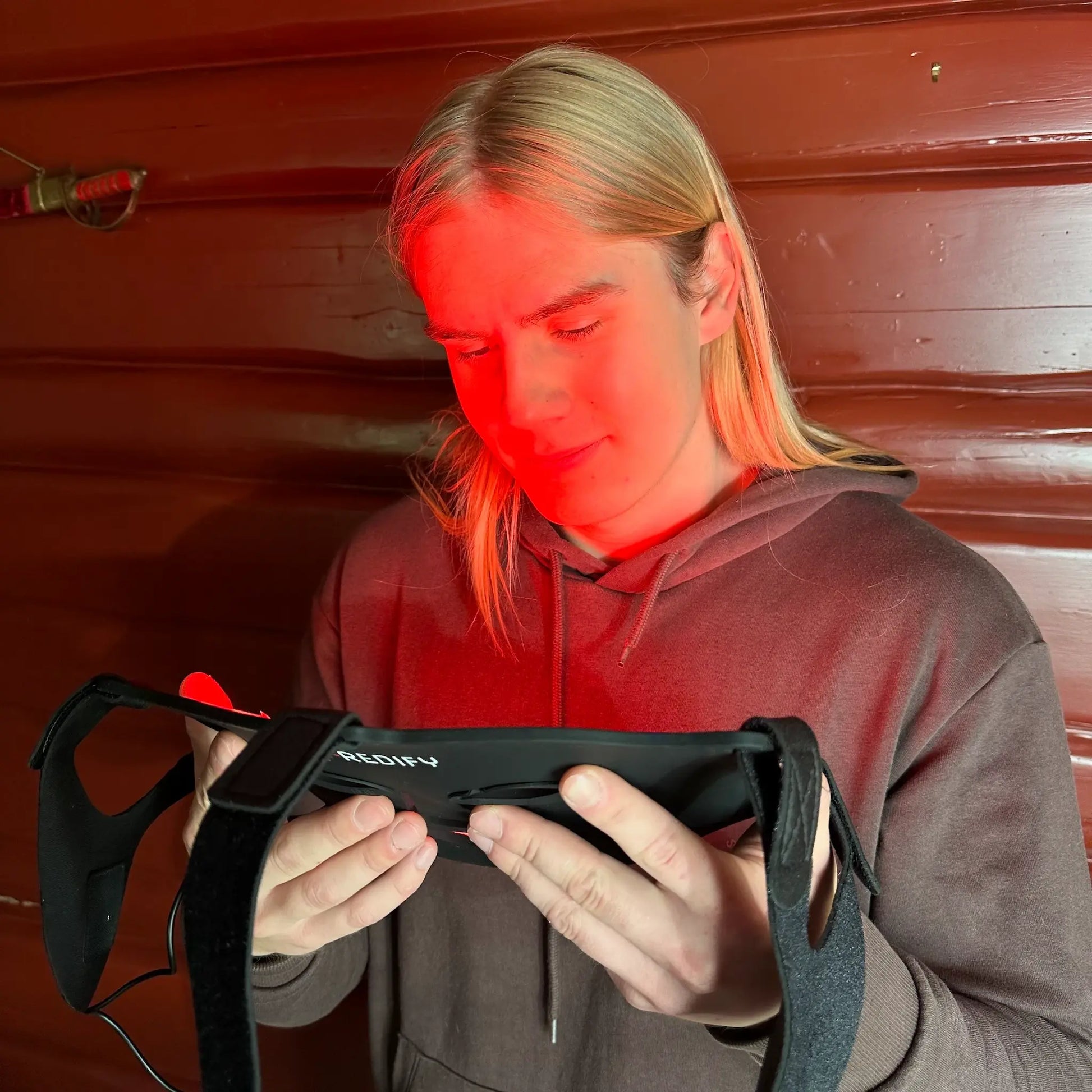 Person holder Redify glow led ansiktsmaske